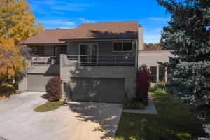 View of front of property with driveway, a chimney, roof with shingles, and a garage