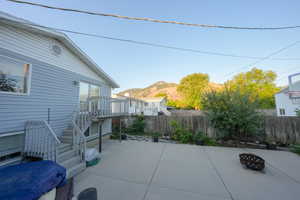 Fenced backyard featuring an outdoor fire pit, a patio area, stairway, and a deck with mountain view