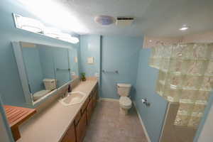Bathroom with a textured ceiling, vanity, and a shower