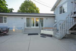 View of patio / terrace with a hot tub, french doors, entry steps, and stairs