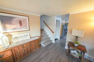 Hallway with crown molding, wood finished floors, and stairs