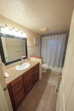 Bathroom with wainscoting, a textured ceiling, vanity, shower / bath combination with curtain, and tile patterned flooring