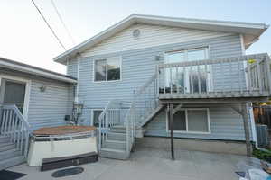Back of property featuring a hot tub, a patio area, and stairway