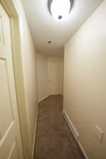 Hallway with carpet flooring and baseboards
