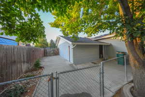 View of home's exterior featuring a gate, a fenced backyard, roof with shingles, and a patio area