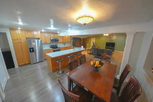 Dining space with a textured ceiling, light wood-type flooring, and decorative columns