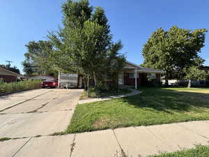 View of front facade with driveway, a front lawn, and brick siding