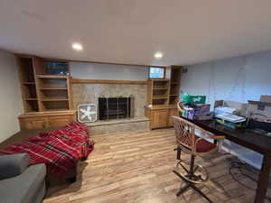 Office with light wood-style flooring, a tiled fireplace, and recessed lighting