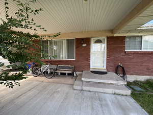 Property entrance featuring brick siding and covered porch
