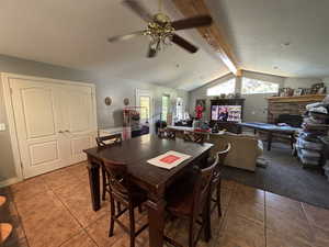 Dining area with a ceiling fan, light tile patterned floors, and a stone fireplace
