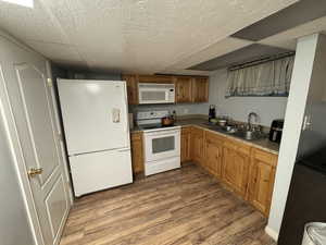 Kitchen featuring white appliances, wood finished floors, and brown cabinetry