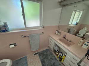 Half bathroom featuring tile walls, wainscoting, vanity, and tile patterned floors
