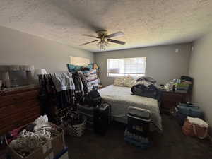 Carpeted bedroom featuring a textured ceiling and a ceiling fan