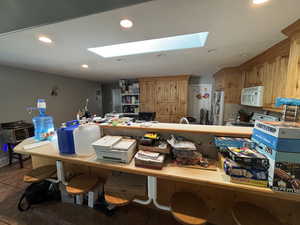 Kitchen with a skylight, tile patterned flooring, recessed lighting, white microwave, and freestanding refrigerator