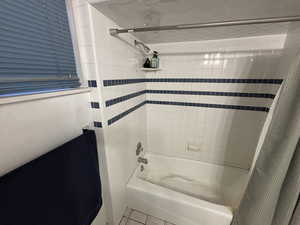 Bathroom featuring shower / bathtub combination with curtain and tile patterned flooring