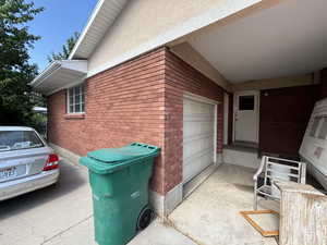View of side of home with brick siding, a garage, and stucco siding