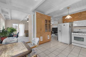 Kitchen with a ceiling fan, white appliances, glass insert cabinets, a wood ceiling with exposed beams, and wooden walls