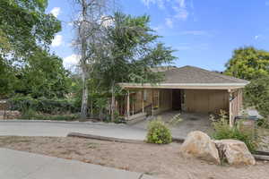 View of front facade with roof with shingles, brick siding, and an attached carport