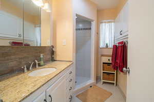 Bathroom featuring vanity, a shower stall, and tasteful backsplash