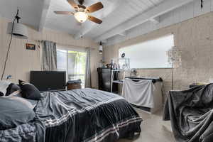 Carpeted bedroom with wood walls, a wooden ceiling with exposed beams, and a ceiling fan