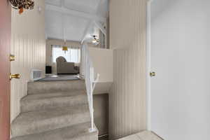 Staircase featuring beam ceiling, a ceiling fan, and wood walls