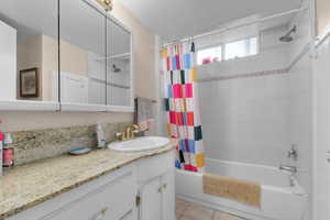 Full bath with vanity, shower / tub combo, and tile patterned flooring