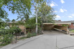 View of front of home featuring brick siding, concrete driveway, an attached carport, and a shingled roof