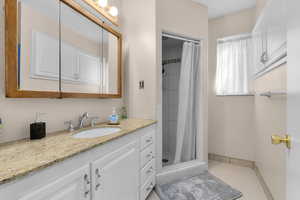 Full bath with vanity, a shower stall, and tile patterned flooring