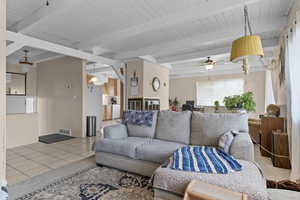 Living room with beam ceiling, tile patterned flooring, and ceiling fan