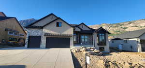 Modern farmhouse style home with a standing seam roof, a metal roof, a mountain view, stone siding, and driveway