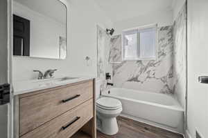 Full bath featuring vanity, crown molding, wood finished floors, and tub / shower combination