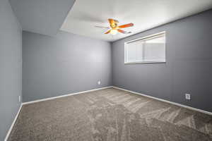 Carpeted empty room featuring ceiling fan and baseboards