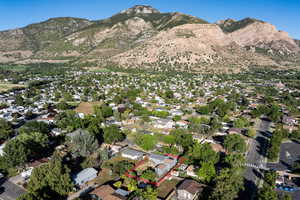 Aerial view of property and surrounding area with property boundaries highlighted, a mountainous background, and nearby suburban area