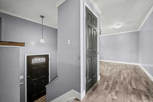 Entryway featuring ornamental molding and wood finished floors