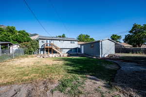 Rear view of property featuring a fenced backyard, an outdoor structure, and stairway