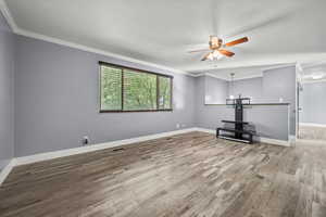Unfurnished living room with ornamental molding, wood finished floors, and ceiling fan
