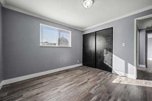 Unfurnished bedroom featuring ornamental molding, a closet, and wood finished floors