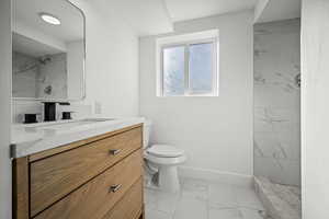 Full bathroom with marble look tile flooring, vanity, and a marble finish shower