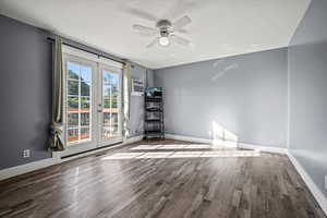 Empty room featuring french doors, a ceiling fan, wood finished floors, and a wall unit AC