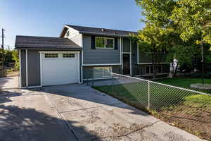 Split foyer home with concrete driveway, a garage, and roof with shingles