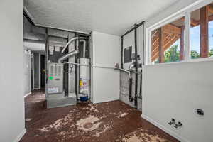 Utility room with gas water heater, heating unit, and electric panel