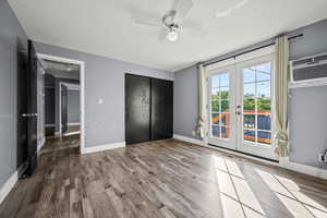 Unfurnished bedroom featuring french doors, access to exterior, wood finished floors, and a closet