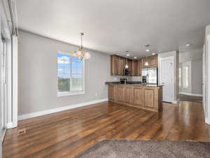 Kitchen with a peninsula, appliances with stainless steel finishes, recessed lighting, dark wood-type flooring, and a chandelier
