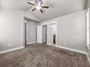 Unfurnished bedroom with lofted ceiling, light colored carpet, ensuite bath, and a ceiling fan