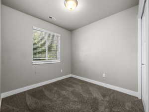 Empty room featuring dark carpet and baseboards