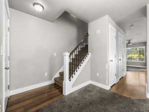Stairs with wood finished floors and ceiling fan