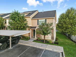 View of front facade featuring uncovered parking, stone siding, roof with shingles, and stucco siding