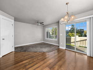 Spare room featuring ceiling fan, wood finished floors, a chandelier, and a textured ceiling