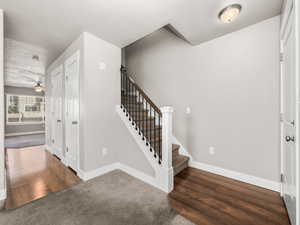 Entrance foyer featuring stairway, wood finished floors, carpet, and a textured ceiling