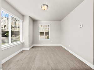 Carpeted empty room featuring baseboards and a textured ceiling